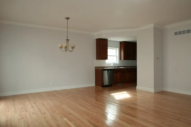 a view of kitchen and empty room with wooden floor