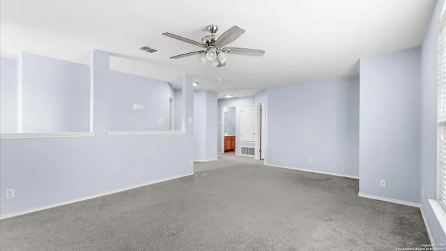 an empty room with ceiling fan and windows