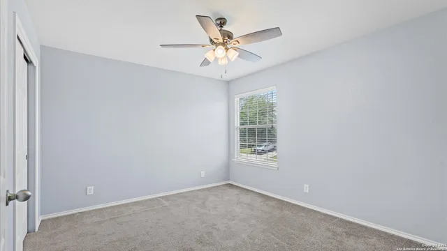 an empty room with window and ceiling fan