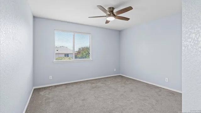 an empty room with a window and a fan