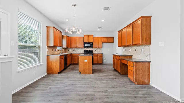 a kitchen with stainless steel appliances granite countertop a stove top oven a sink dishwasher and a refrigerator with wooden floor