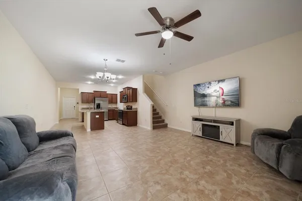 a living room with furniture kitchen view and a chandelier