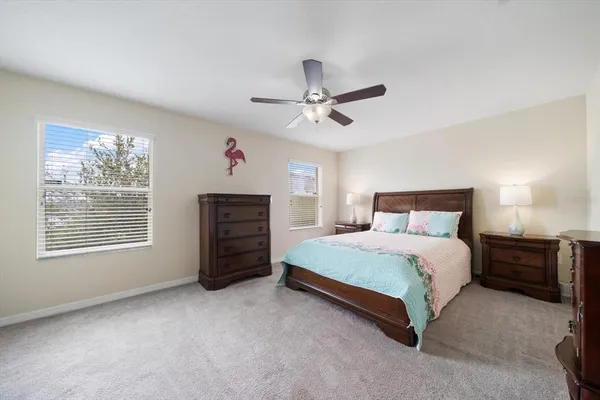 a spacious bedroom with a bed a dresser and a chandelier