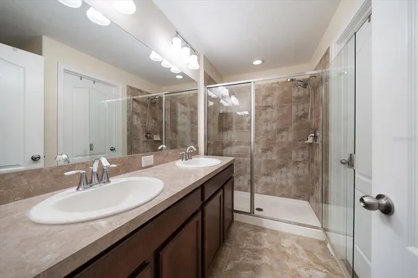 a bathroom with a shower sink vanity granite and mirror