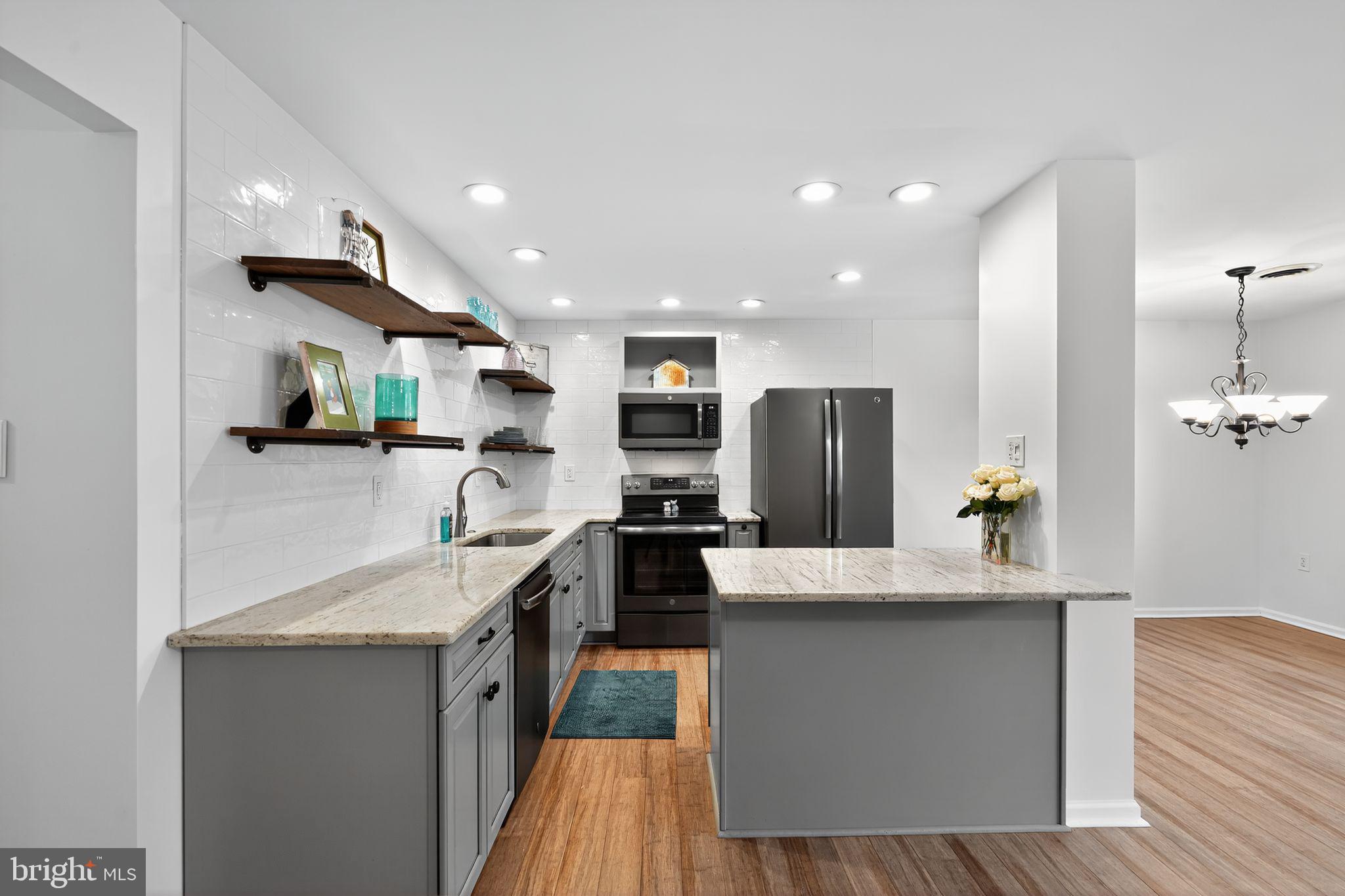 908 Yardley Commons Yardley, PA 19067 - Photo 8 of 28 a large kitchen with stainless steel appliances kitchen island granite countertop a large counter top and wooden floors