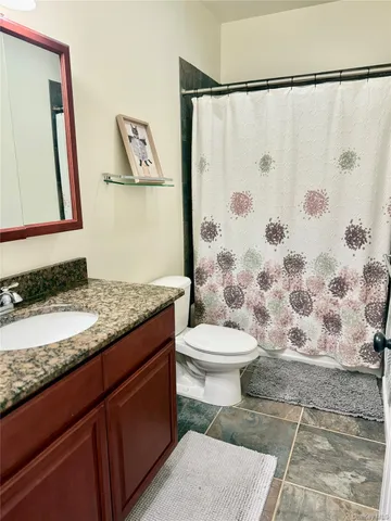 a bathroom with a granite countertop sink toilet and shower