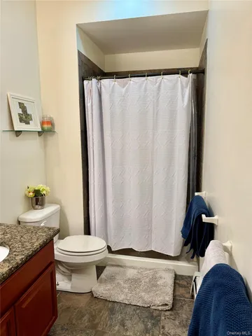 a bathroom with a granite countertop toilet and a sink