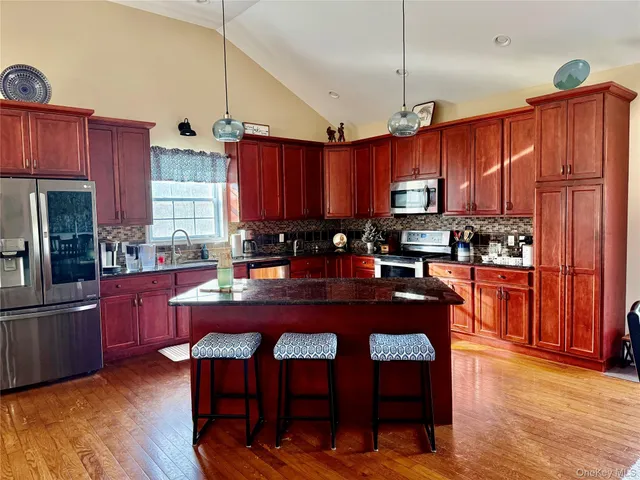 a kitchen with stainless steel appliances granite countertop a stove a refrigerator a sink dishwasher a dining table and chairs with wooden floor