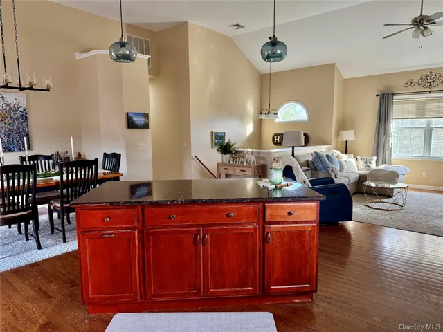 a kitchen with granite countertop a dining table chairs refrigerator and wooden floor