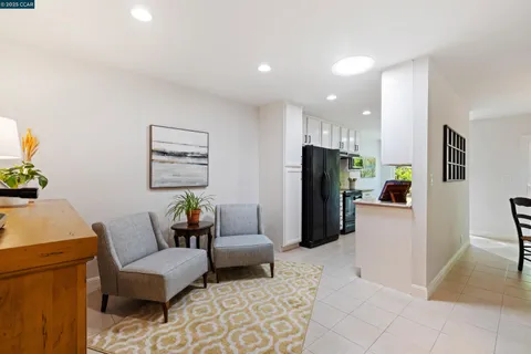 a living room with furniture and a refrigerator