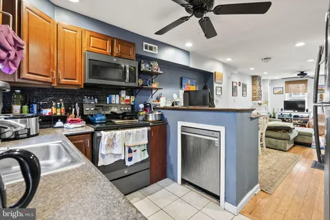 a kitchen with stainless steel appliances granite countertop a stove top oven a sink a dining table and chairs with wooden floor