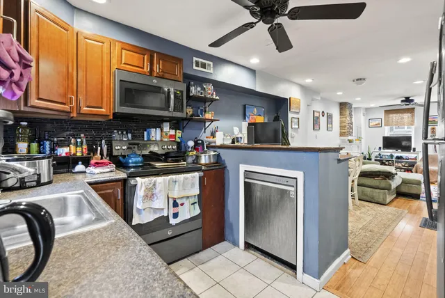 a kitchen with stainless steel appliances granite countertop a stove top oven a sink a dining table and chairs with wooden floor