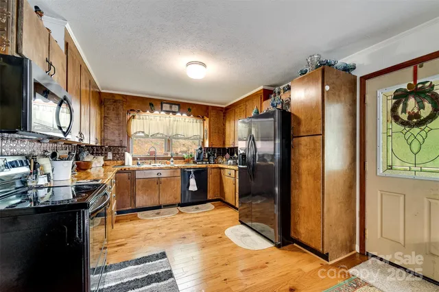 a kitchen with stainless steel appliances granite countertop a stove top oven a sink dishwasher a dining table and chairs with wooden floor