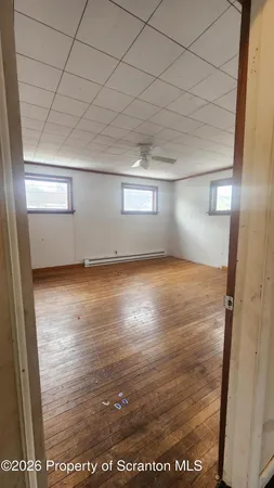 a view of empty room with wooden floor and fan