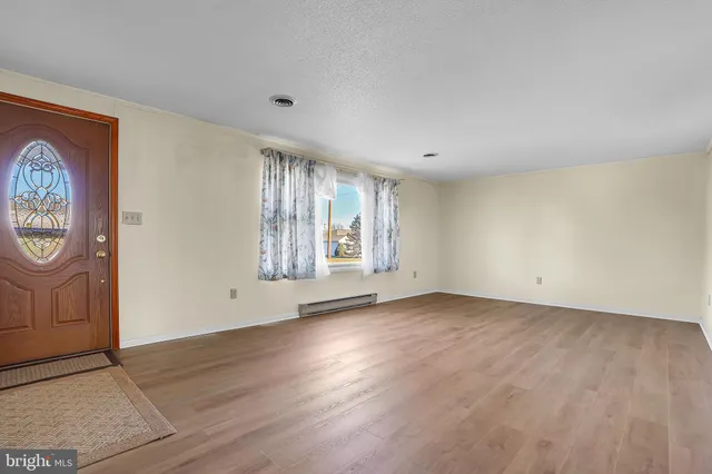 an empty room with wooden floor and window