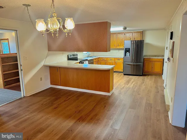 a view of a kitchen with wooden floor and a refrigerator