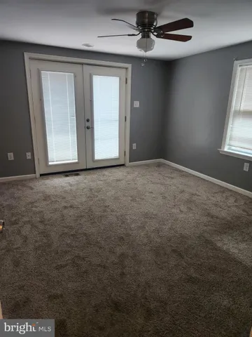 an empty room with windows and fan