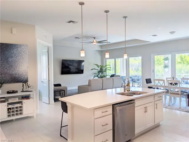 a room with stainless steel appliances kitchen island granite countertop a sink a stove and a flat screen tv