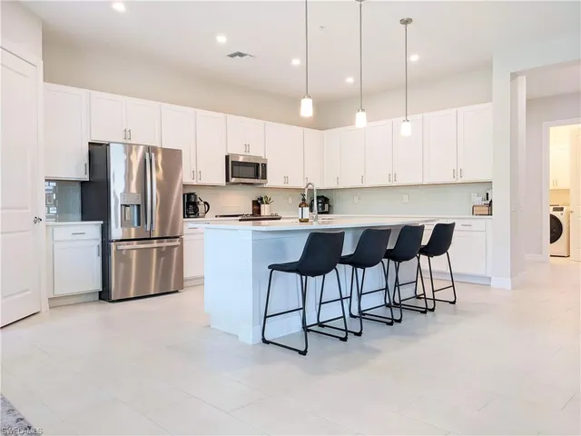 a kitchen with stainless steel appliances a refrigerator a stove a sink a dining table and chairs