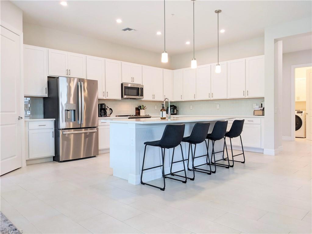 178 Indies Drive East, Unit 201 Naples, FL 34114 - Photo 7 of 31 a kitchen with stainless steel appliances a refrigerator a stove a sink a dining table and chairs