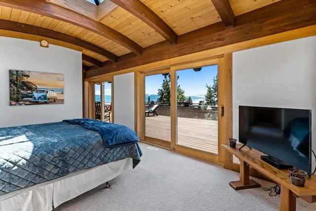 a bedroom with a large bed and a flat tv screen on dresser