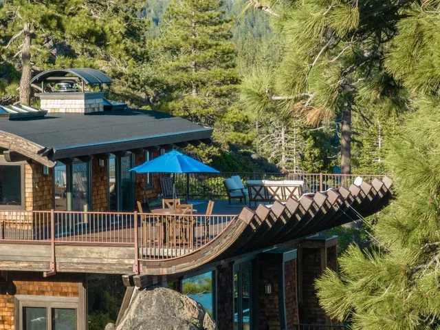 a view of a patio with table and chairs under an umbrella with barbeque grill and wooden fence