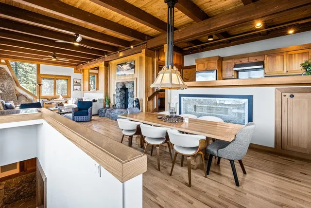 a dining room with wooden floor a chandelier a wooden table and chairs
