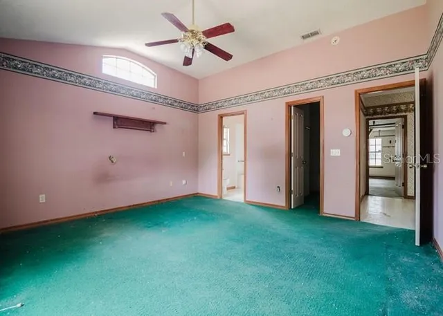 a view of an empty room with closet and a ceiling fan