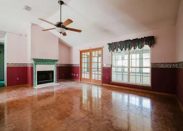 a view of an empty room with wooden floor fireplace and a window