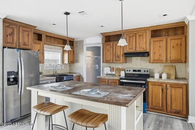 a kitchen with stainless steel appliances granite countertop a stove refrigerator a sink dishwasher and a stove