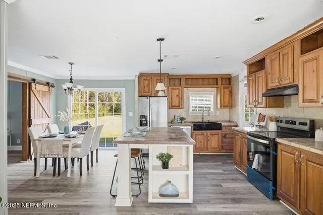 a kitchen with stainless steel appliances granite countertop a stove top oven a sink dishwasher a dining table and chairs with wooden floor