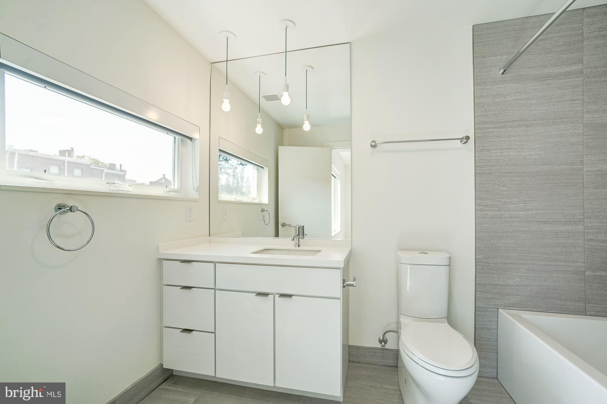 446 Ridge Street Northwest Washington, DC 20001 - Photo 7 of 24 a bathroom with a toilet a sink a mirror a window and vanity