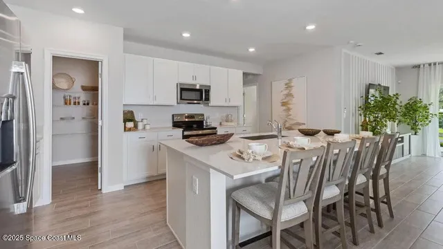 a kitchen with stainless steel appliances a table chairs refrigerator and microwave