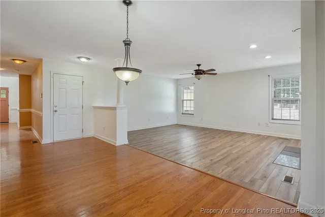 a view of empty room with wooden floor and ceiling fan