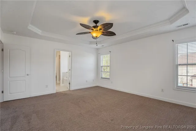 a view of an empty room with window and chandelier fan