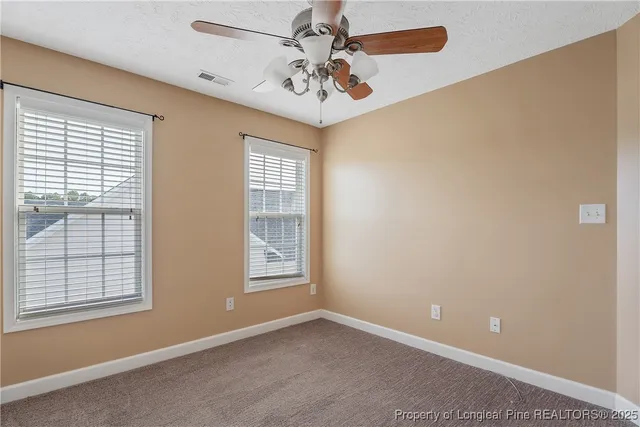 an empty room with windows and fan