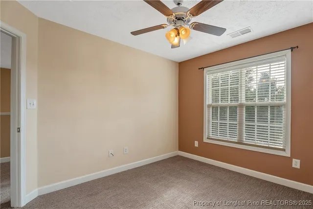 an empty room with a window and a ceiling fan