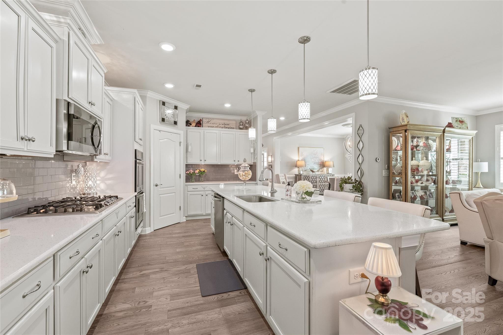 5002 Samoa Ridge Drive Lancaster, SC 29720 - Photo 13 of 45 a large white kitchen with kitchen island a stove a sink a chimney wooden floor and cabinets