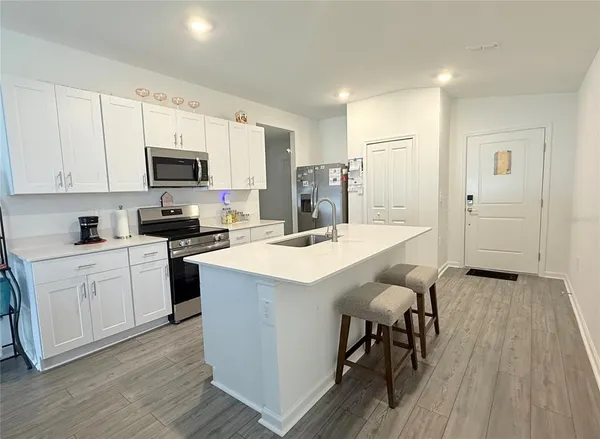 a kitchen with kitchen island granite countertop wooden floors and white appliances