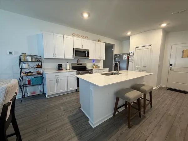 a kitchen with a sink a microwave a refrigerator and cabinets