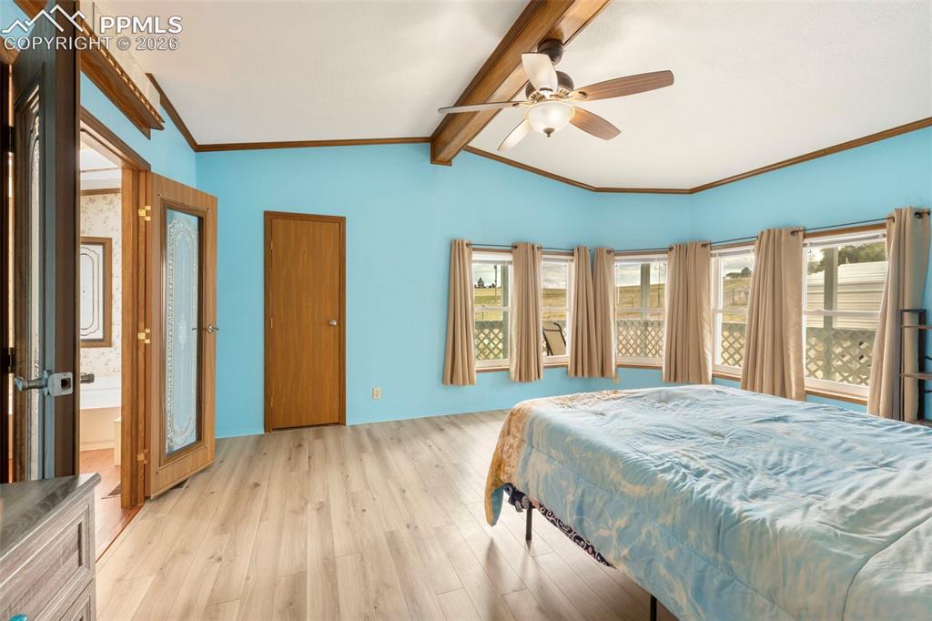 13335 Gymkhana Road Peyton, CO 80831 - Photo 26 of 38 Room featuring light wood-finish flooring, a bay window with multiple panes, exposed ceiling beams, and a ceiling fan with integrated lighting