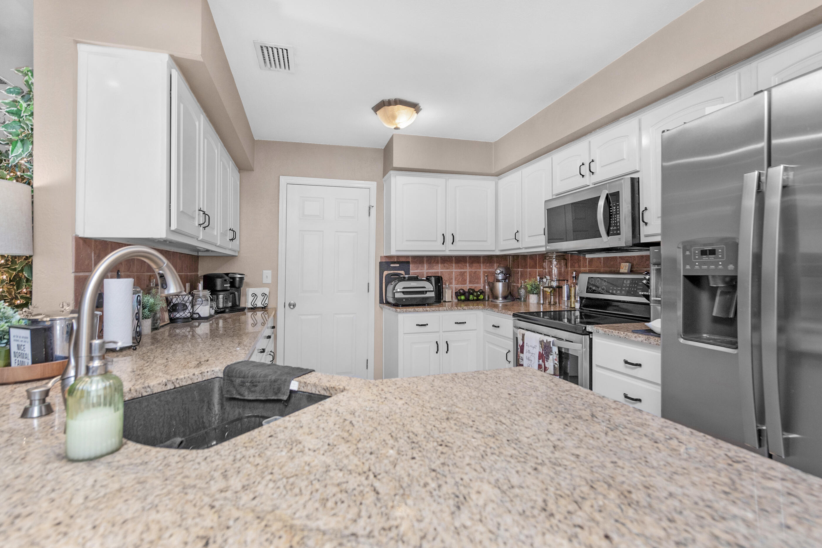 1984 Pine Ranch Drive Navarre, FL 32566 - Photo 23 of 45 a kitchen with stainless steel appliances granite countertop a sink refrigerator and microwave