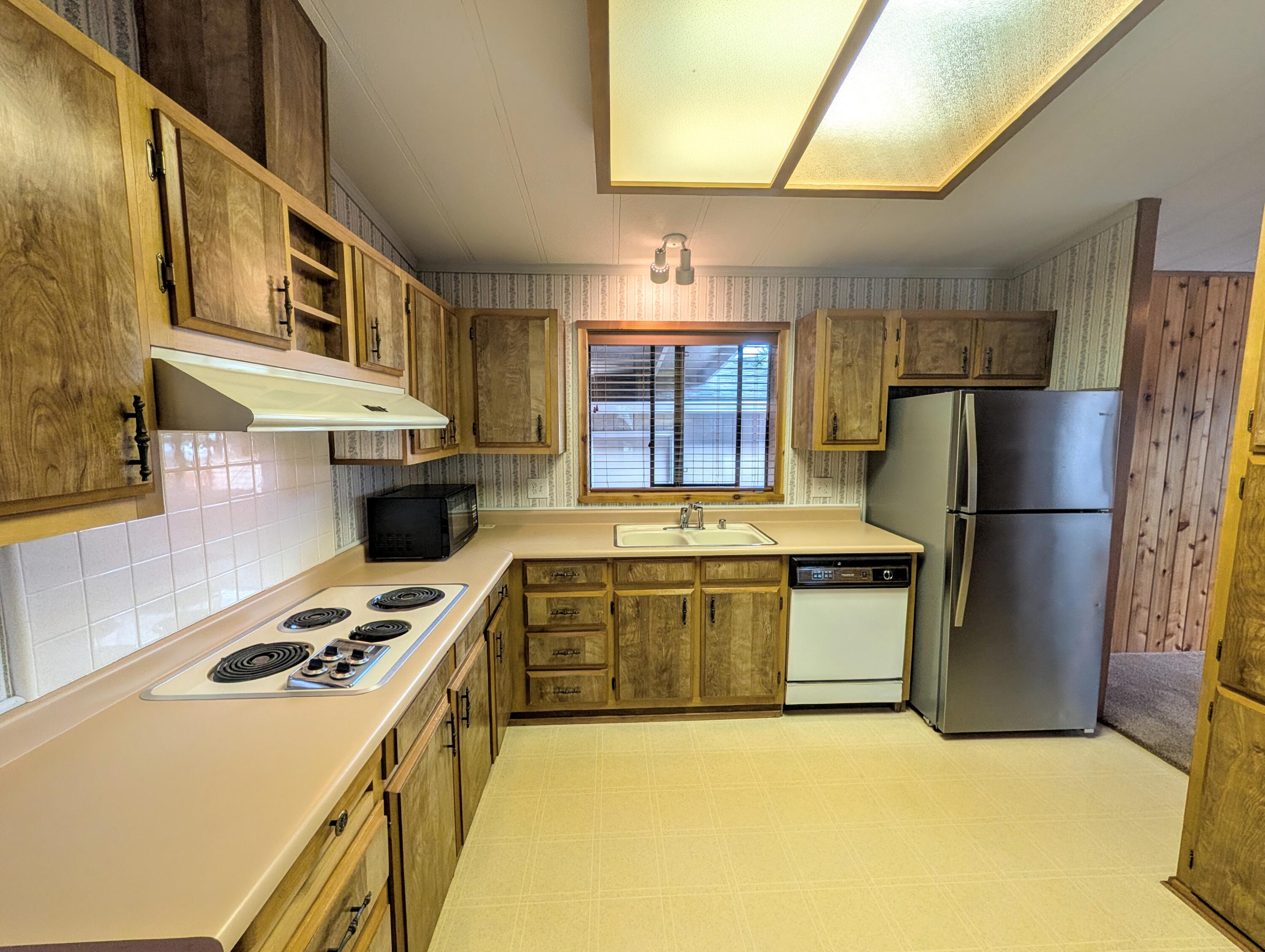 20735 Valentine Street, Unit 6 Bend, OR 97701 - Photo 6 of 26 a kitchen with stainless steel appliances granite countertop a refrigerator a stove and a sink with wooden floor