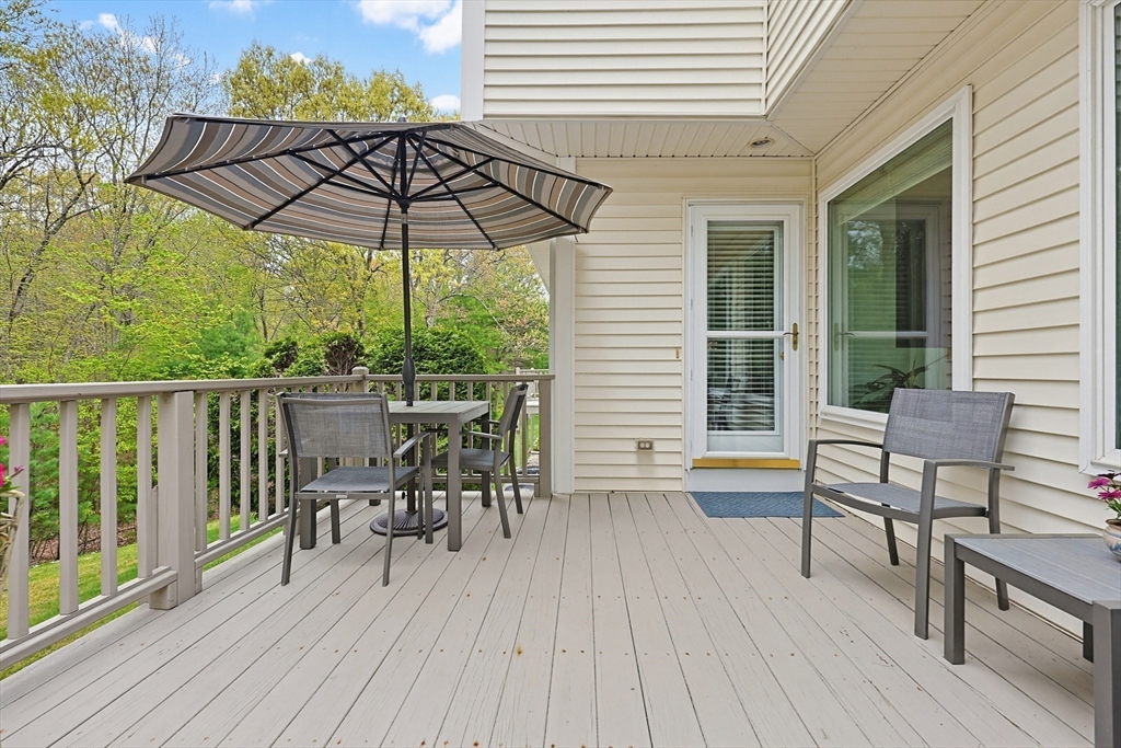3002 Maple Brook Road, Unit 3002 Bellingham, MA 02019 - Photo 33 of 42 a view of a deck with table and chairs under an umbrella with wooden floor