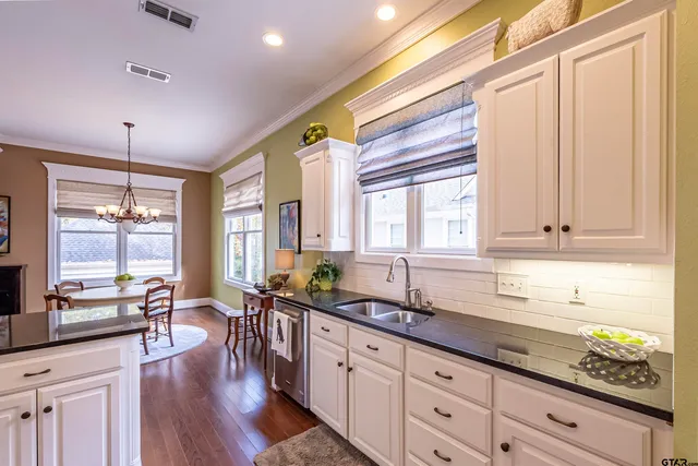 a large kitchen with granite countertop a large window and white cabinets