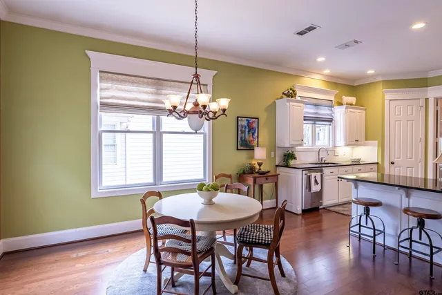 a dining room with wooden floor a chandelier a wooden table and chairs