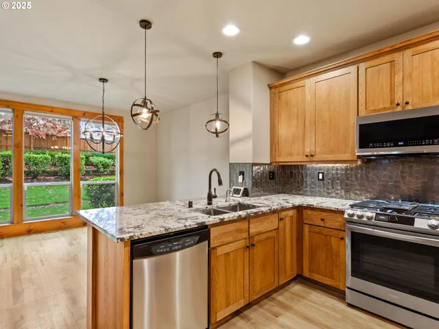 a kitchen with stainless steel appliances granite countertop a stove a refrigerator and a sink