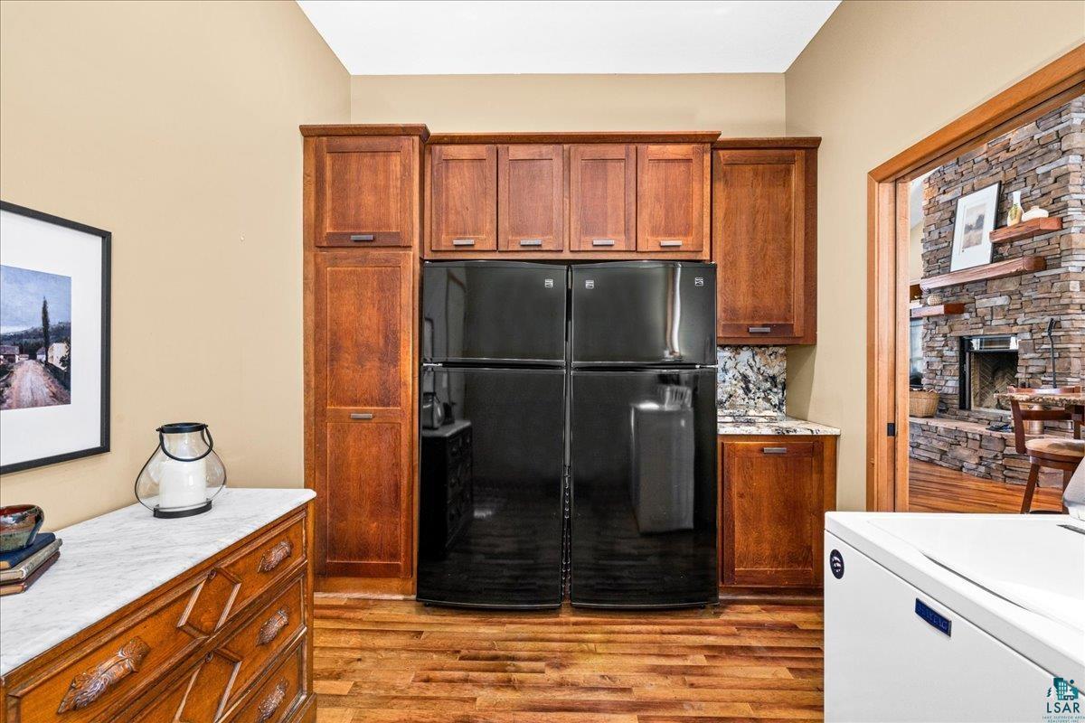 92598 Spells Road Sturgeon Lake, MN 55783 - Photo 15 of 60 Kitchen with freestanding refrigerator, washer / clothes dryer, a fireplace, and wood finish cabinetry