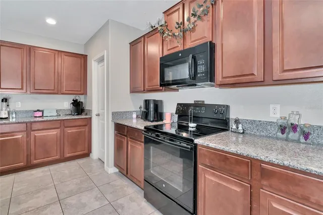 a kitchen with granite countertop a table chairs a sink dishwasher and cabinets
