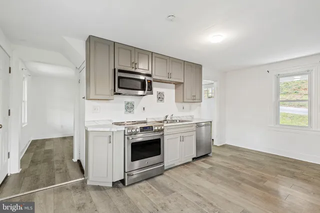 a kitchen with stainless steel appliances granite countertop a stove a sink and a microwave